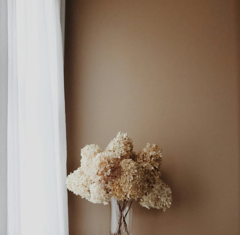 Vase de fleurs séchées sur des livres, symbole d’un espace calme, doux et conscient de ressourcement