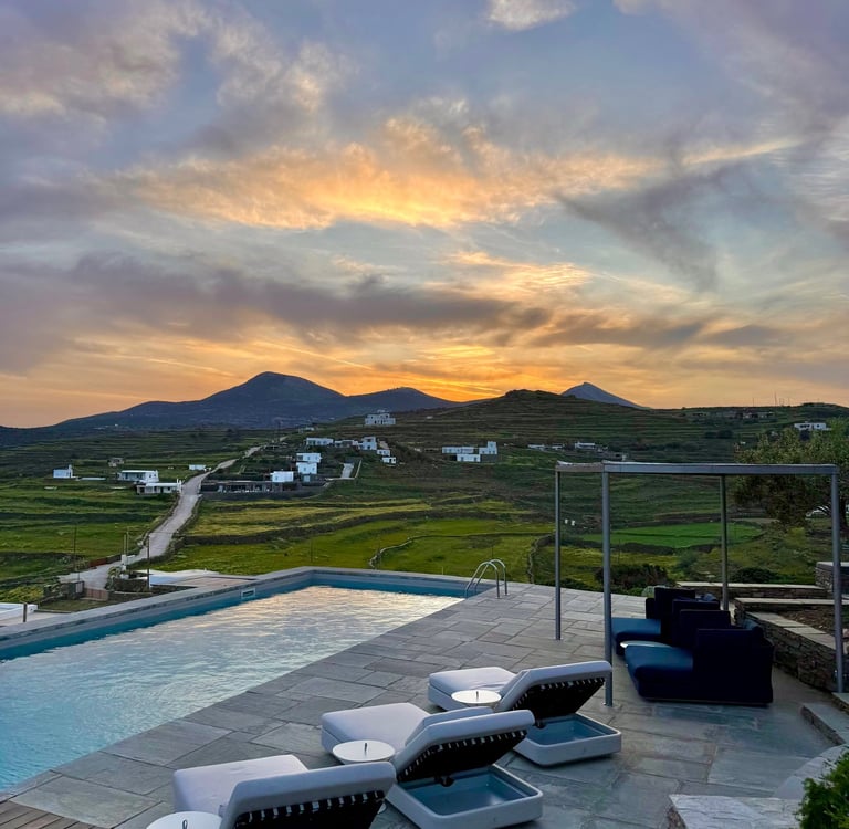 View over the pool onto green hills and small buildings in the distance.