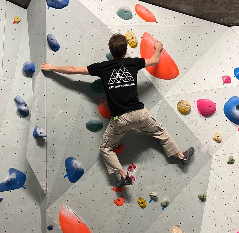 a man is bouldering on a wall in a climbing gym
