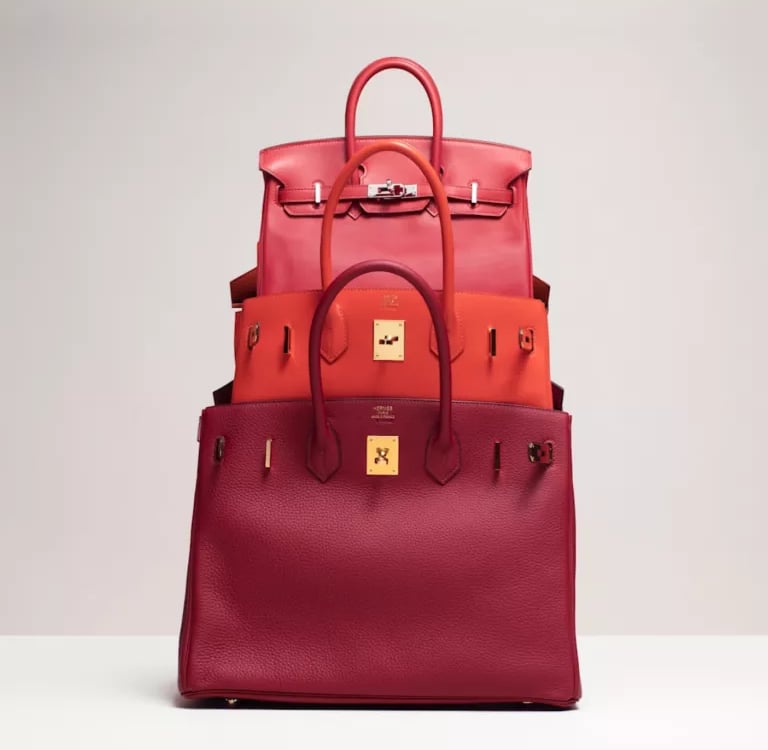 Stacked red and orange luxury Hermes birkin handbags showcasing premium leather craftsmanship.