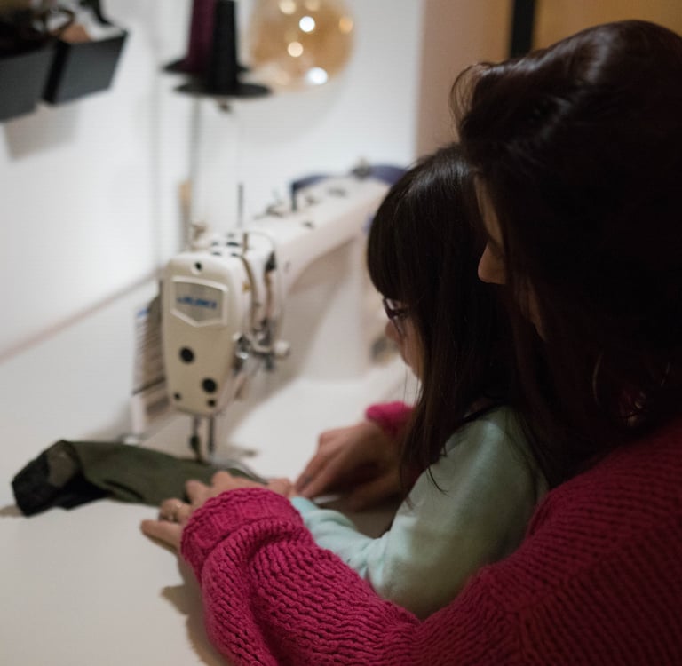 une femme et une petite fille sont en train de coudre un sac banane