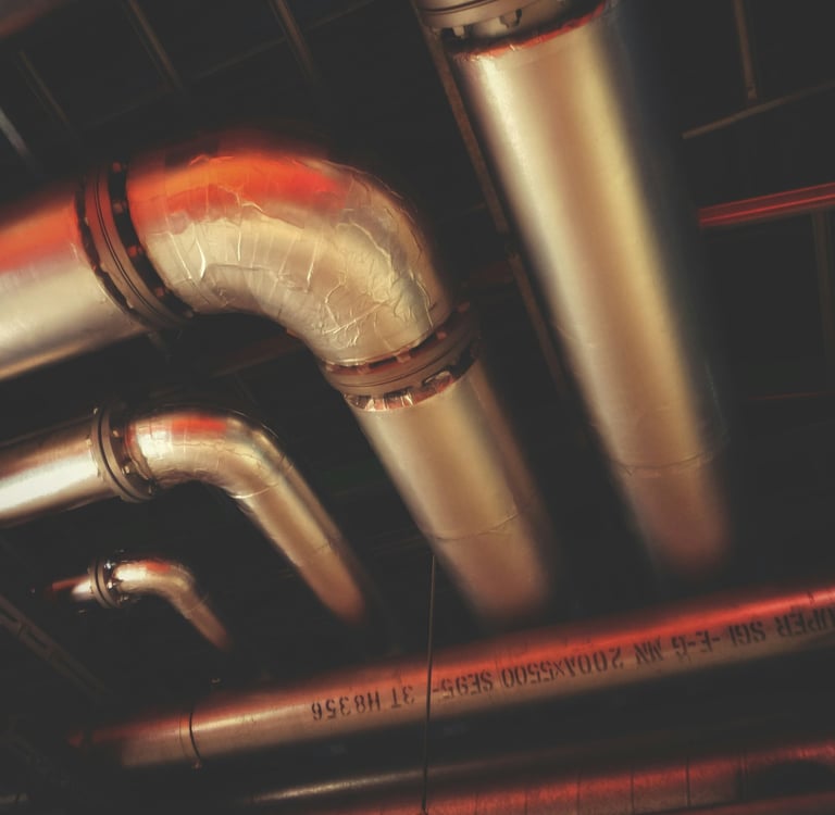 Network of insulated silver pipes on a ceiling.