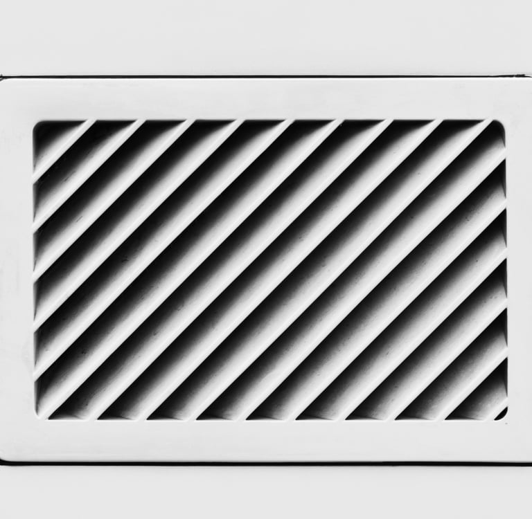 Angled black slats inside a white rectangular vent.