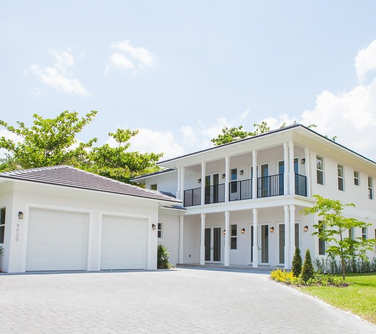 a white luxury home with a large driveway shown and a two door garage
