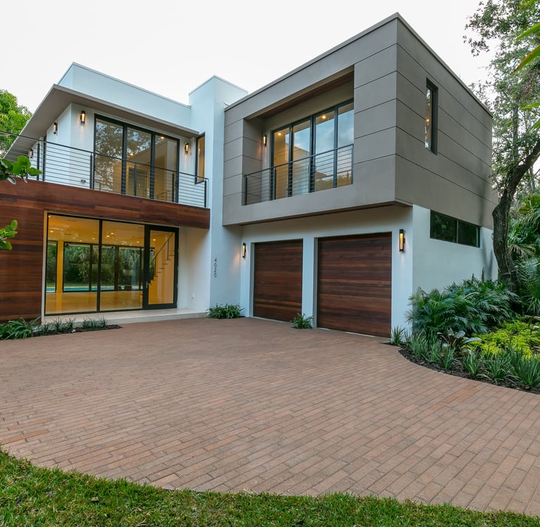 a brick driveway to a square looking custom designed luxury home