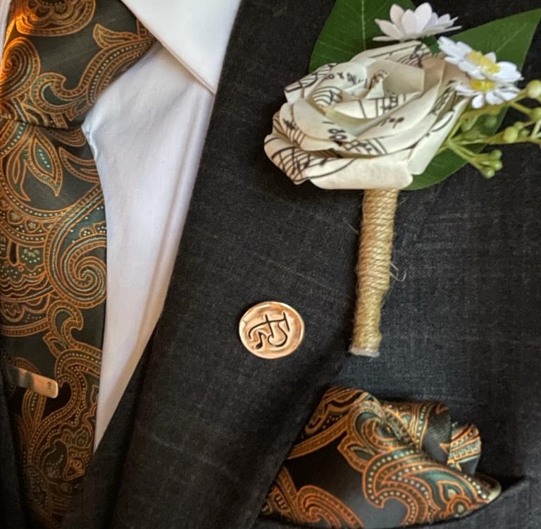 a man in a suit and tie with a flower made from music paper