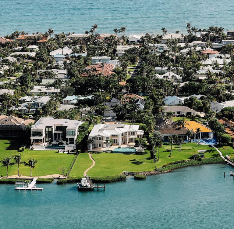 Aerial view of luxury waterfront real estate and coastal homes in a tropical Florida community.