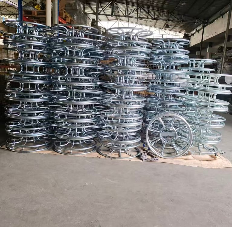 Stacks of industrial galvanized steel metal hose reels in a manufacturing warehouse facility.