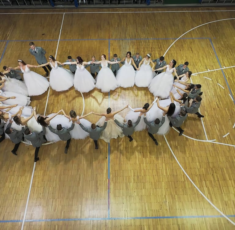 beltéri FPV drónos kép egy sportcsarnokban rendezett szalagavató bálról ahol ovális formában táncol