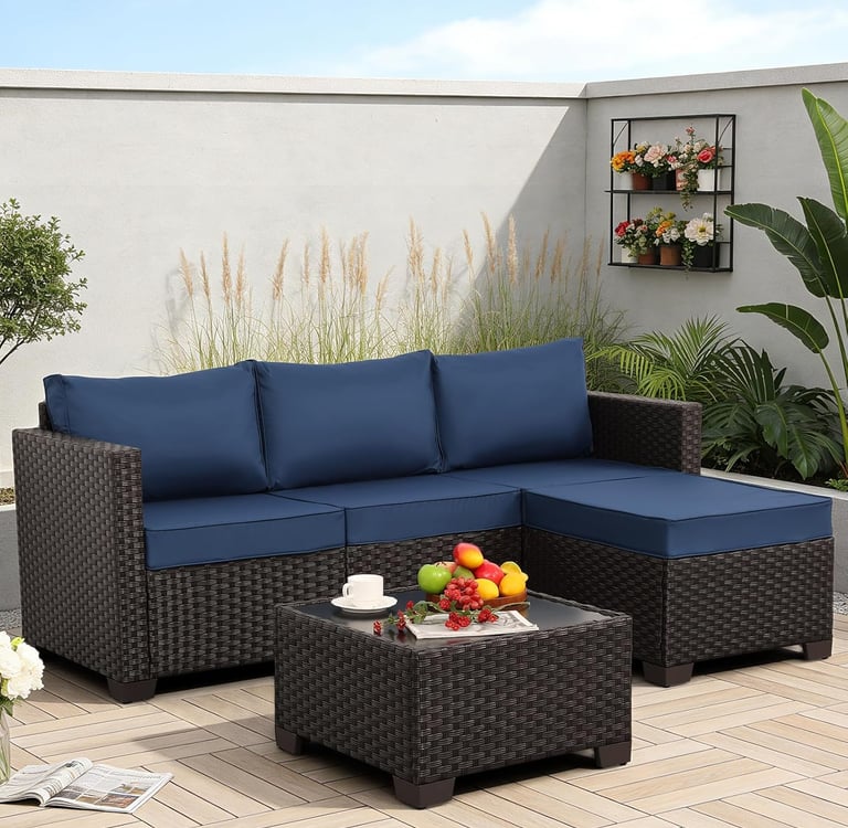 Modern outdoor sectional sofa with navy blue cushions and a matching wicker coffee table on a patio.