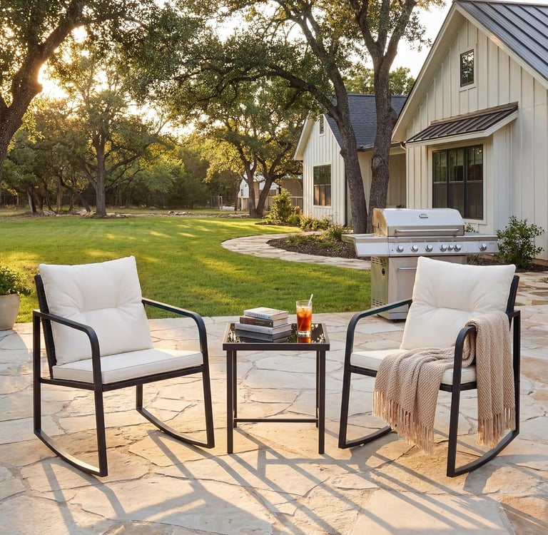 Outdoor patio set with two black metal rocking chairs and a side table on a stone terrace.