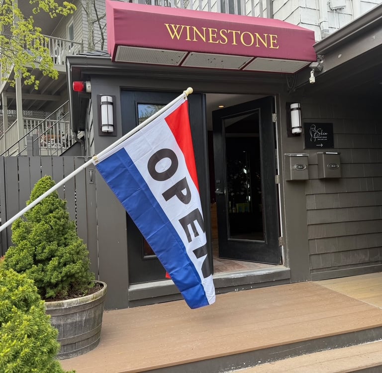 Winestone boutique storefront with a red awning and a tricolor open flag hanging at the entrance.