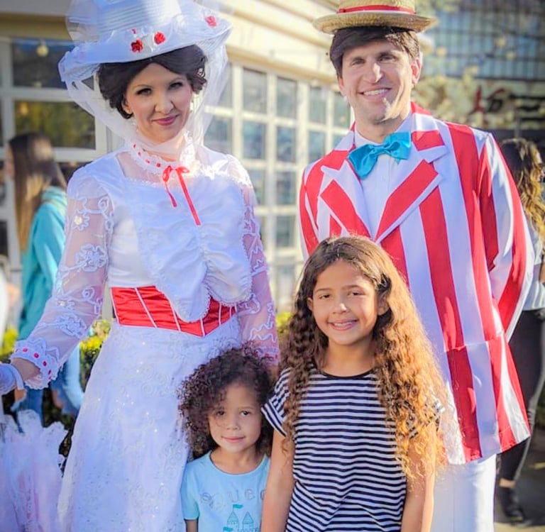 A Chimney Sweep character in a striped barbershop quartet jacket smiles for photo with child.