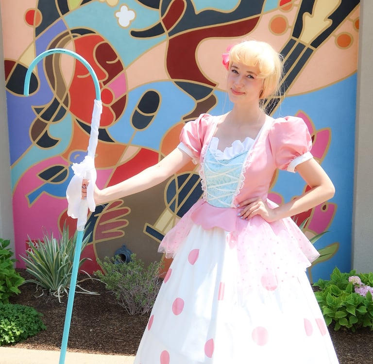 A beautiful girl with a blue shepherd's crook standing against a colorful mural.