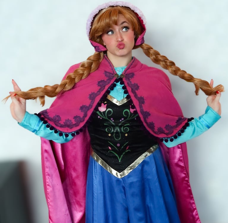 A cosplayer dressed as Princess Anna from Frozen wearing a pink cape and braided wig while making a funny face.