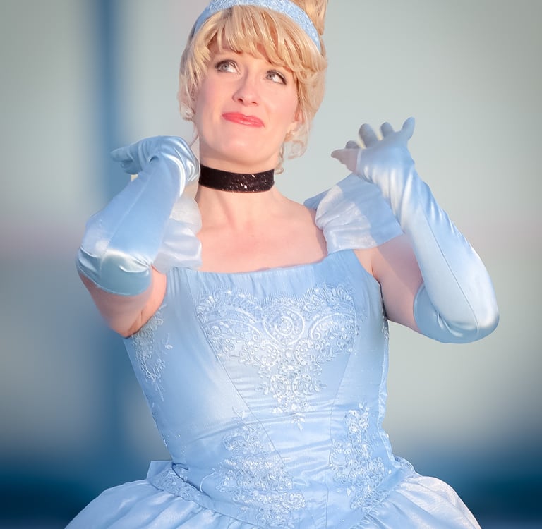 A woman dressed in an ariel cosplay costume featuring a light blue ballgown and matching gloves.