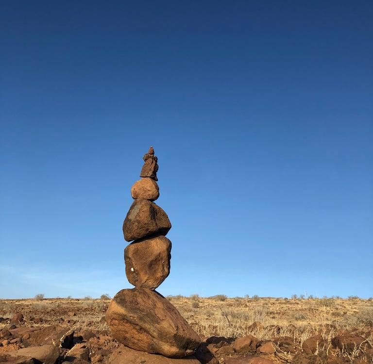 stacked stones on dry land against blue sky