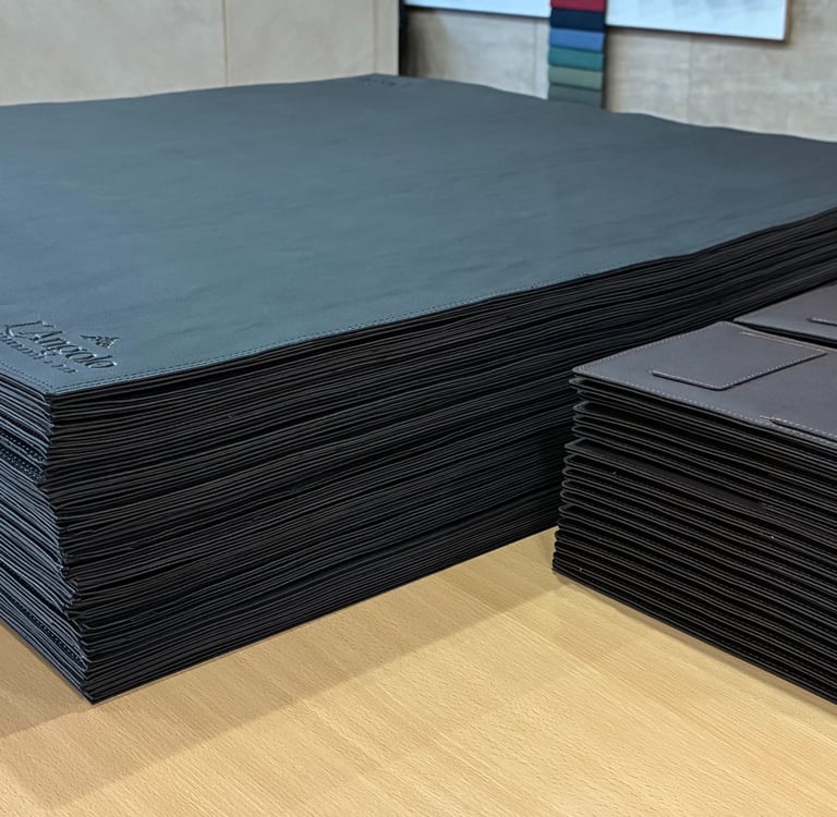 foto de una pila de cubremesas de similcuero y dos pilas de portacuentas de similcuero