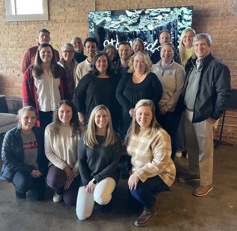 A professional business team smiles for a group photo at a TeamLab by WorkPlay Solutions