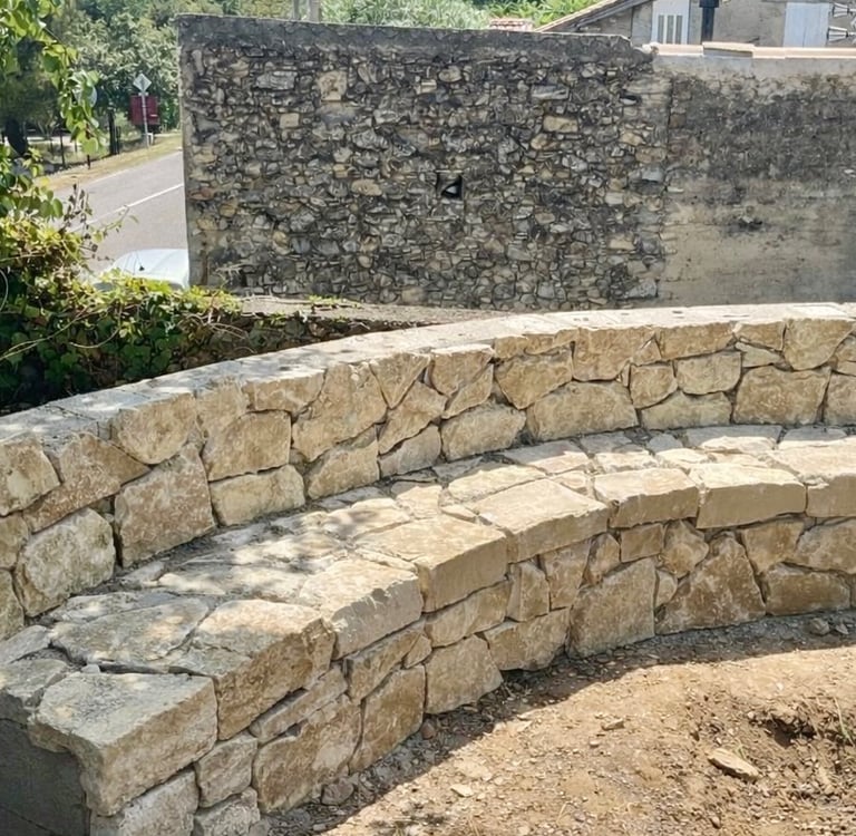 Création d’un banc extérieur en pierre naturelle, intégré à l’aménagement paysager pour un espace es