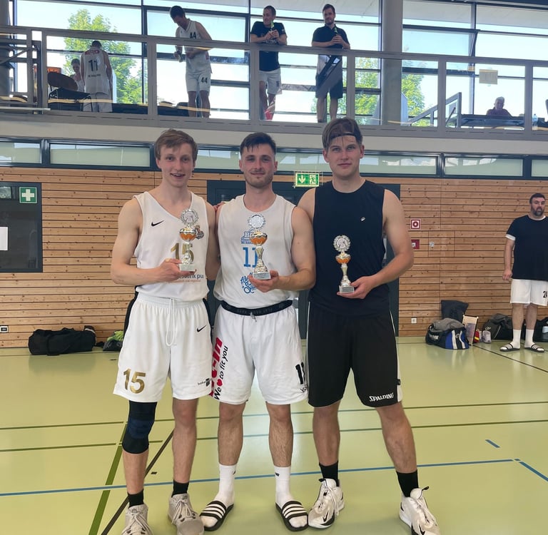 alt="Three basketball players displaying their individual trophies."