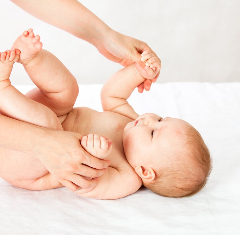 a baby is laying on a bed with a woman's hands
