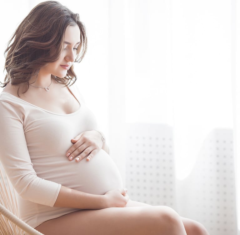 a pregnant woman sitting in a chair holding her belly