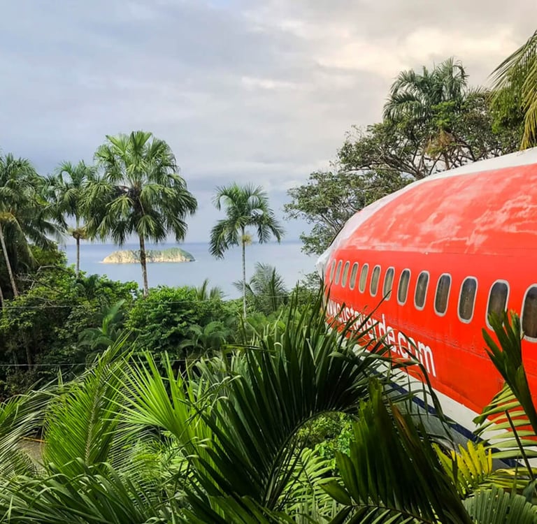 A vintage red airplane converted into a hotel suite nestled in a lush Costa Rican jungle overlooking the ocean.