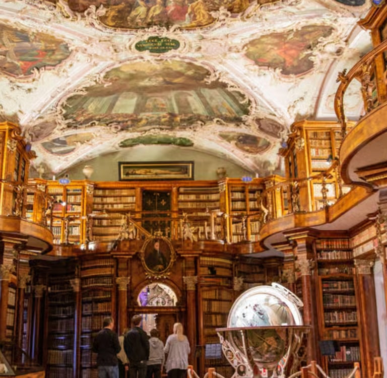 Ornate baroque interior of the Abbey Library of Saint Gall featuring ceiling frescoes and wooden bookshelves.