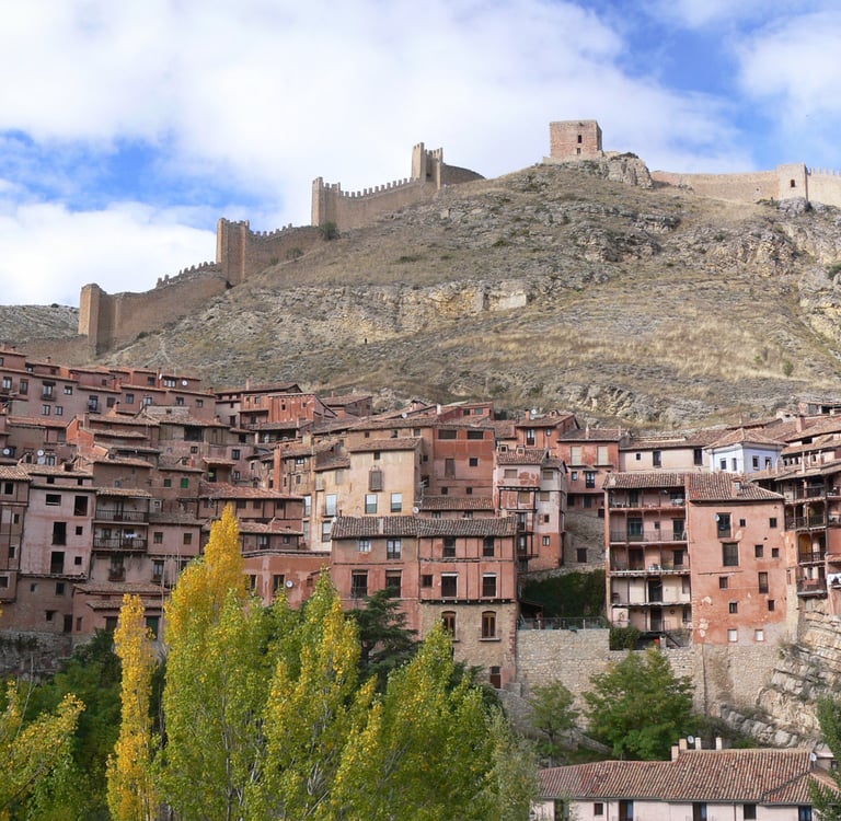 Medieval town of Albarracin with red stone houses and historic castle walls on a Spanish hillside.