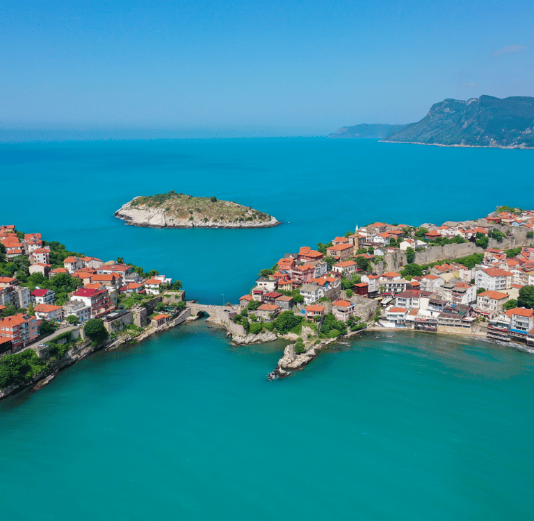 Aerial view of Amasra coastal town with historic red-roofed houses and turquoise Black Sea water.