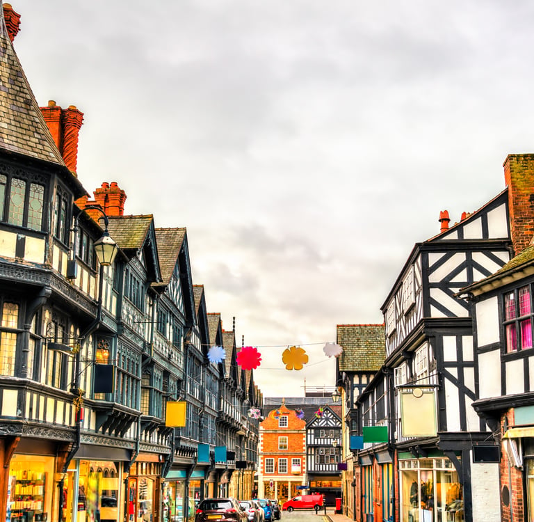 Traditional half-timbered Tudor style buildings and shops lining a historic street in Chester, England.