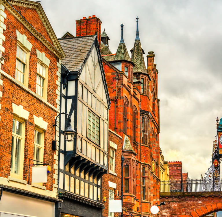 Historic Eastgate Clock and Tudor-style architecture in Chester, England, under a cloudy sky.