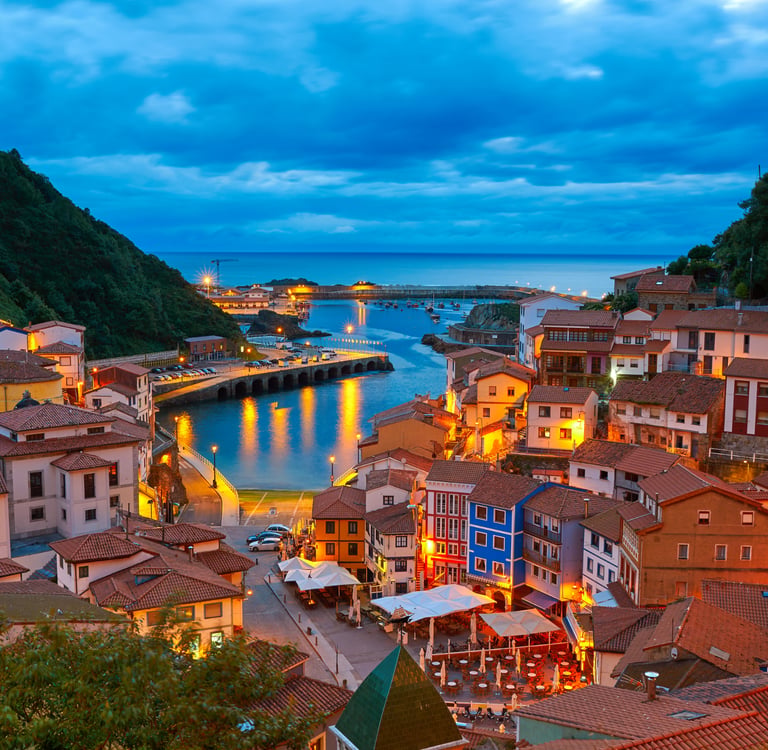 Panoramic evening view of Cudillero fishing village in Asturias, Spain, with colorful houses and harbor.