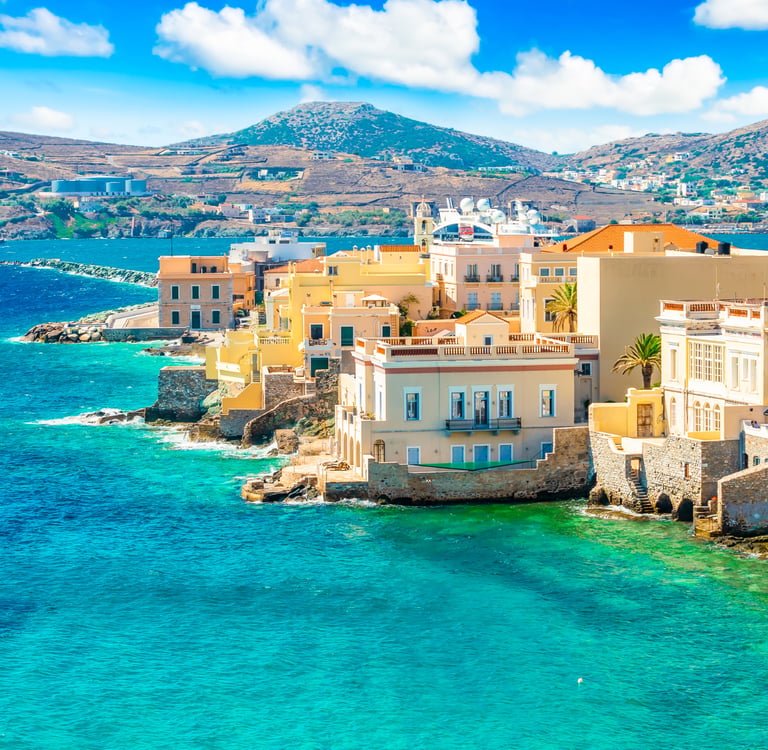 Colorful coastal architecture in Ermoupoli overlooking the turquoise Aegean Sea on Syros island, Greece.