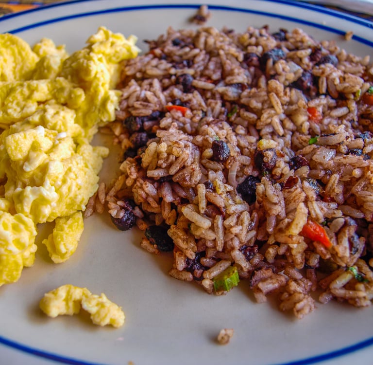 A plate of traditional Costa Rican Gallo Pinto served with fluffy scrambled eggs for breakfast.