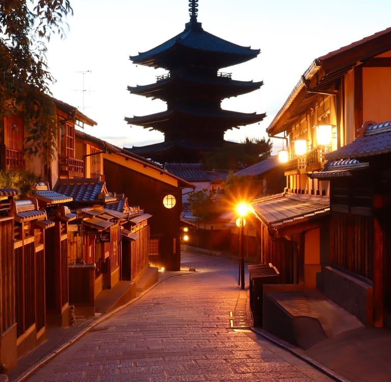 A sunset view of a historic Kyoto street leading toward the Yasaka Pagoda with traditional wooden buildings.