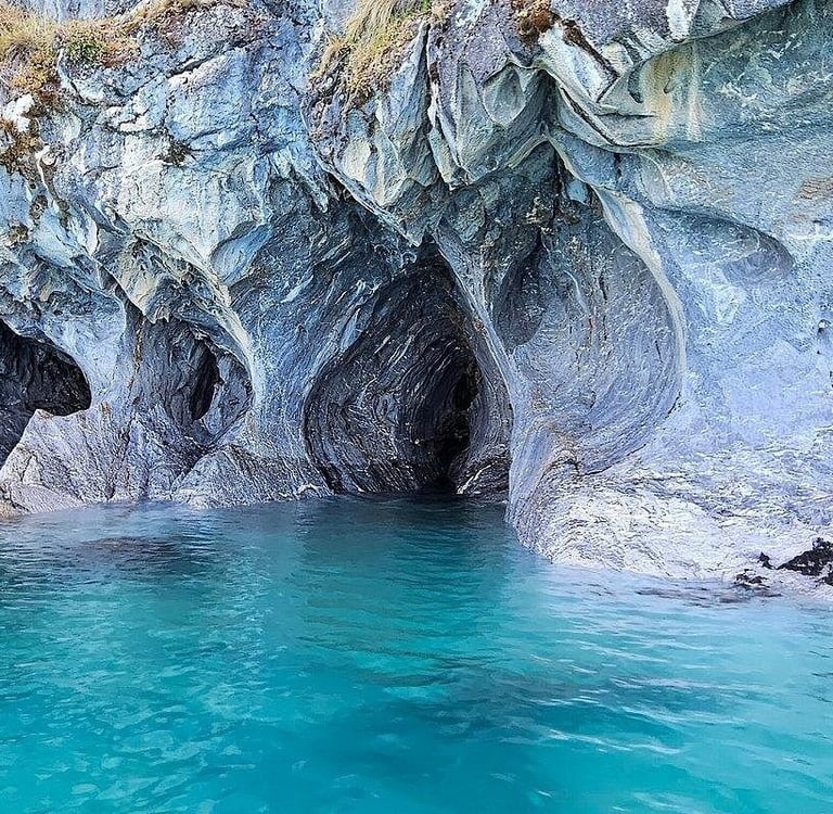 The Marble Caves of Patagonia with sculpted blue rock formations over clear turquoise water in Chile.