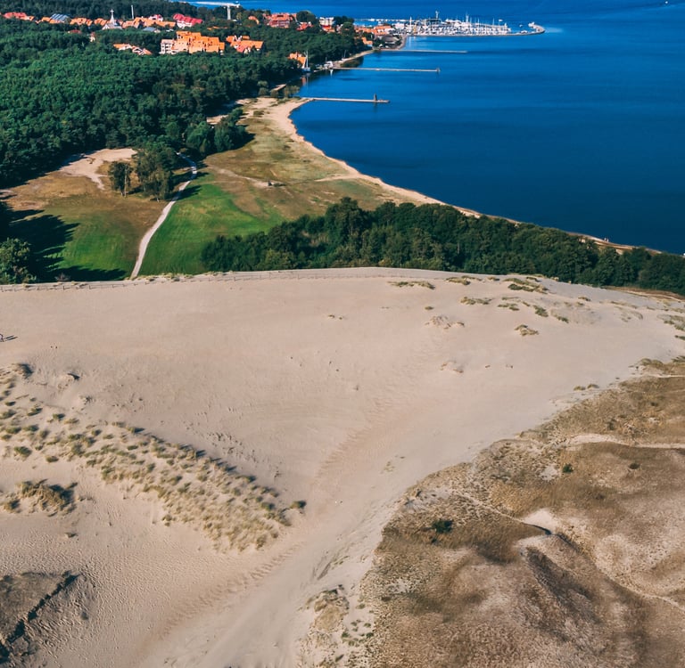 Aerial view of Parnidis Dune in Nida, Lithuania, overlooking the Curonian Lagoon and lush forest.