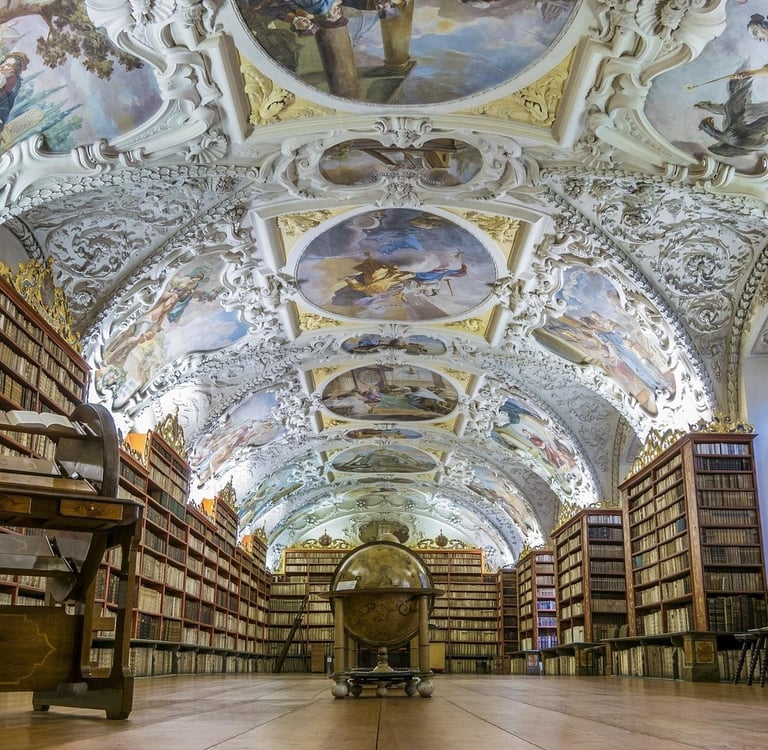 Ornate Baroque ceiling frescoes in the historic Strahov Monastery library with ancient bookshelves and a globe.