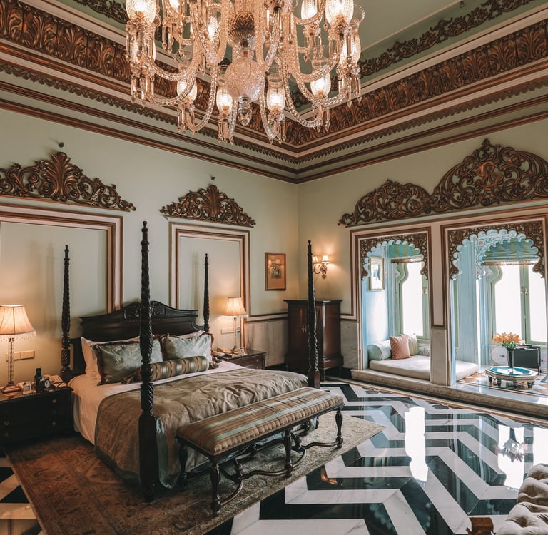 Luxury royal suite with a four-poster bed, ornate crystal chandelier, and marble chevron floors in an Indian palace.