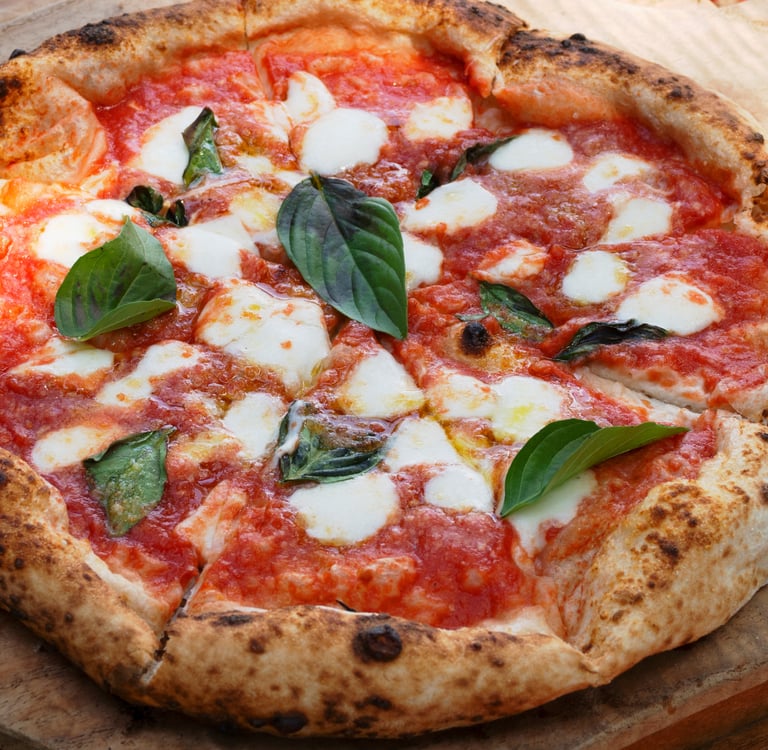 Wood-fired Neapolitan pizza Margherita with fresh buffalo mozzarella, tomato sauce, and basil leaves on a wooden peel.