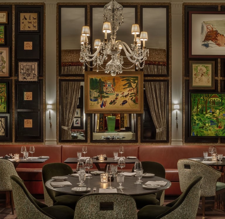 Elegant restaurant dining room with crystal chandelier, gallery wall art, and luxury booths.