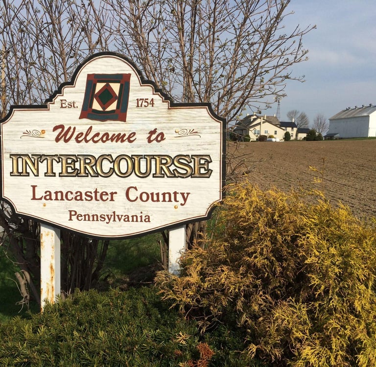 Welcome to Intercourse Lancaster County Pennsylvania road sign near Amish farm country fields.