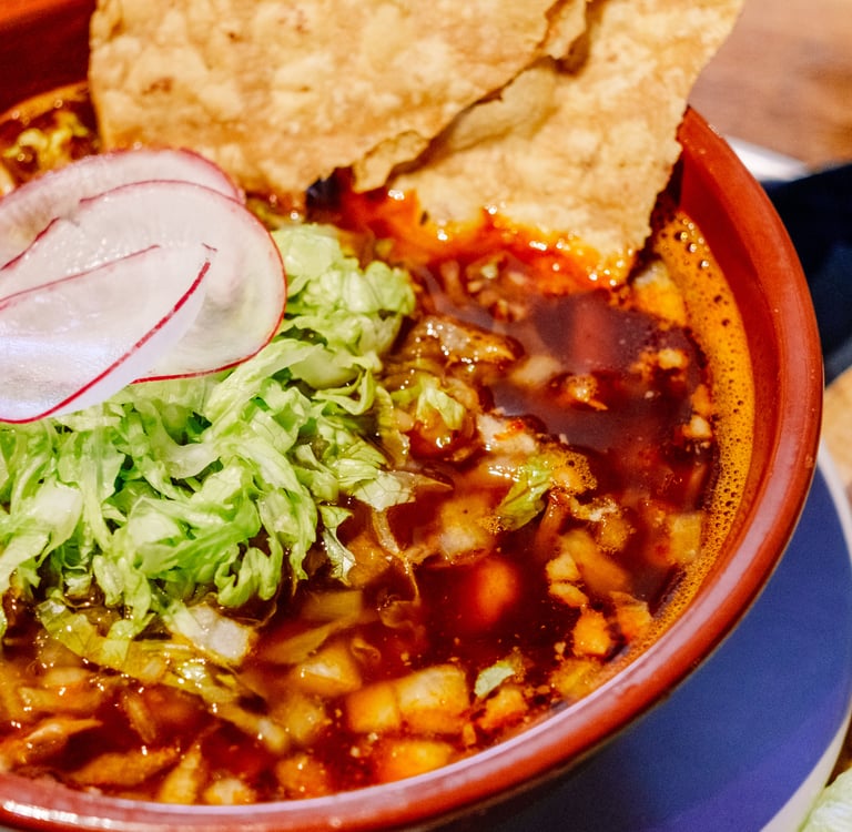 Authentic Mexican pork pozole rojo topped with shredded lettuce, radish, and crispy tostadas.