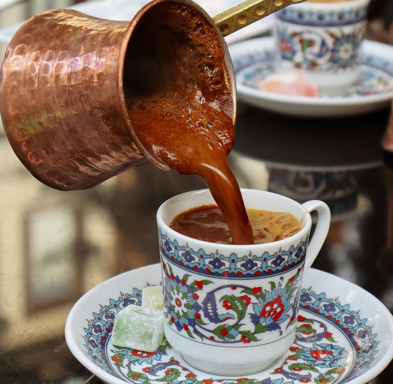 Traditional Turkish coffee being poured from a copper cezve into an ornate ceramic cup.