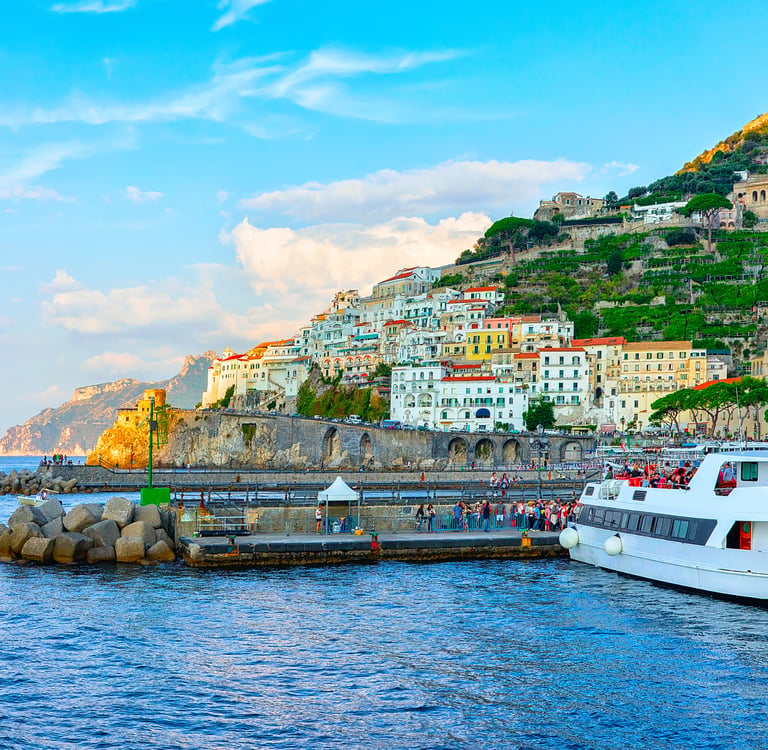 A large white ferry docked at the colorful seaside village of Amalfi on Italy's Amalfi Coast.