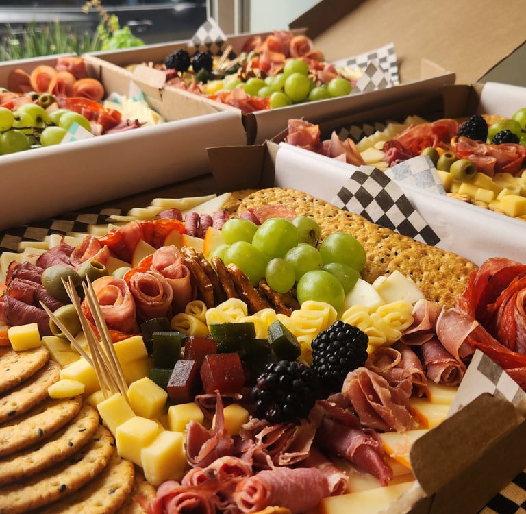 a variety of food, cheese, fruit and crackers in boxes
