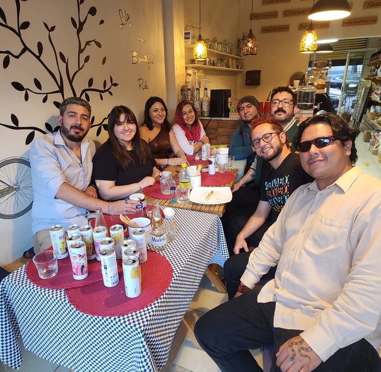 A group of diverse friends smiling at a restaurant table with drinks and beers.