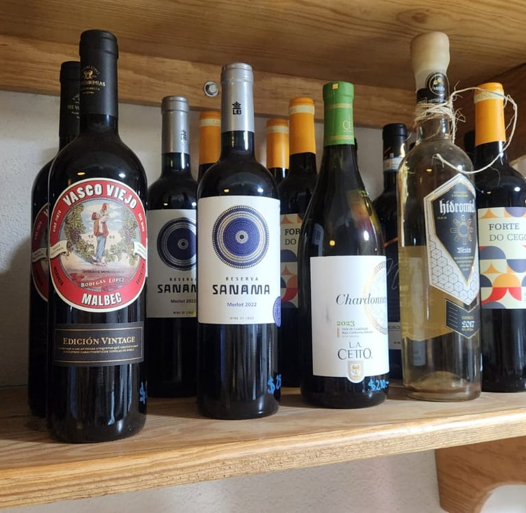 A collection of red and white wine bottles, including Malbec and Chardonnay, on a rustic wooden shelf.